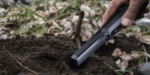 A SUNPOW pinpointer probes fresh soil in a dug hole